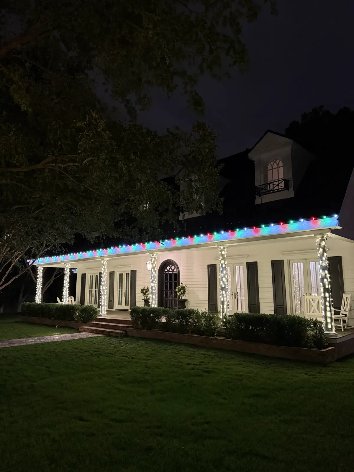 White porch home with multicolor roofline lights